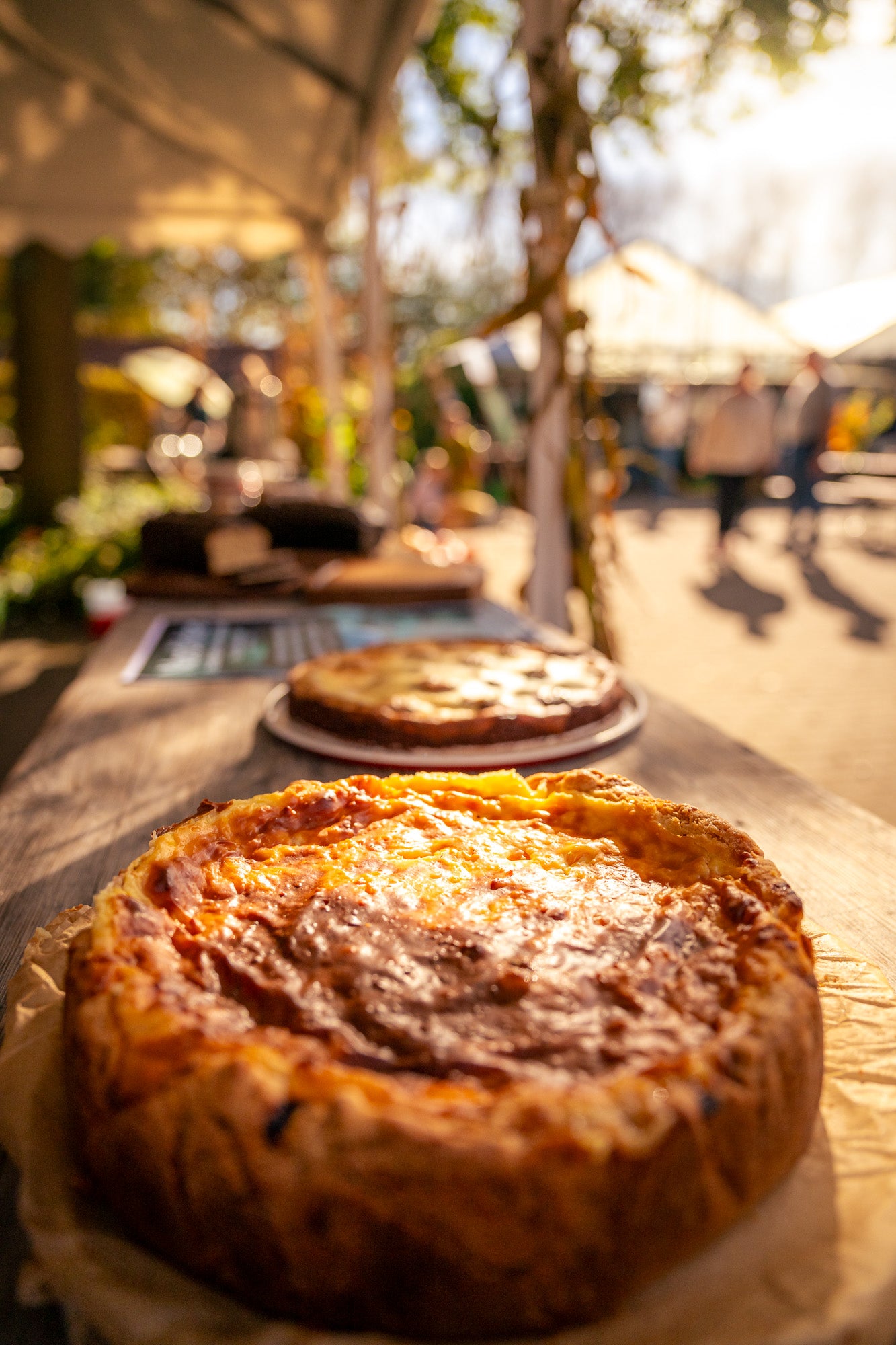 Catering in Münster – Auf dem Bild sieht man zwei Zwiebelkuchen bei schönem Herbstwetter und Sonnenschein. Im Hintergrund steht unscharf frisches Brot.  